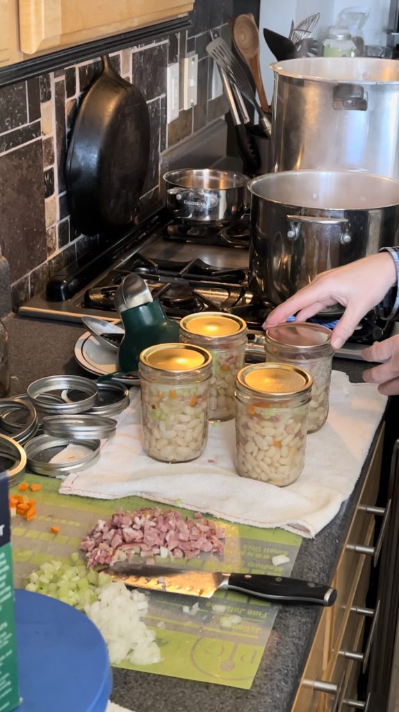 Adding the lids to the ham and bean soup being pressure canned